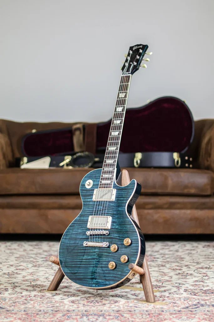 Gibson Les Paul Custom electric guitar in translucent blue finish with flamed maple top on a wooden stand.