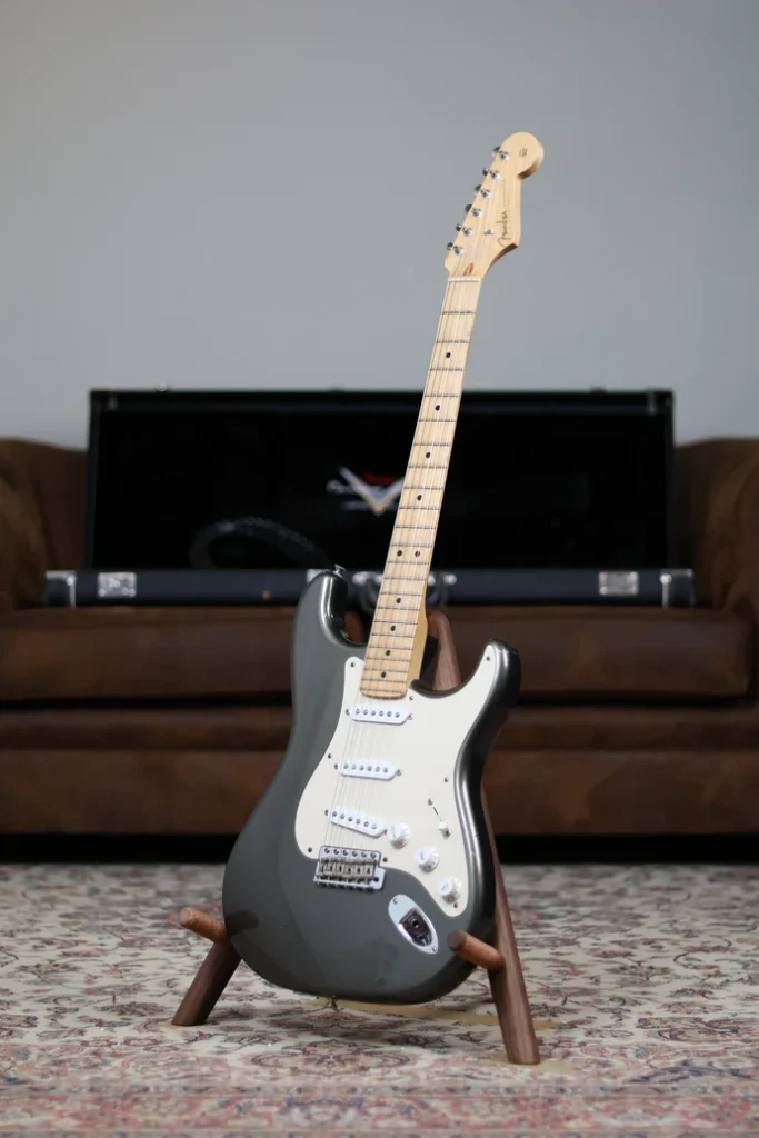 Fender Stratocaster electric guitar in charcoal frost metallic finish with maple fretboard on a wooden stand.
